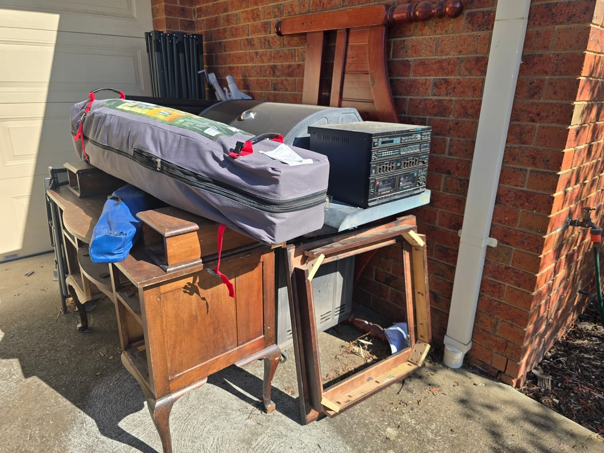 Old BBQ, oven and junk by a brick wall before household rubbish removal in Melbourne
