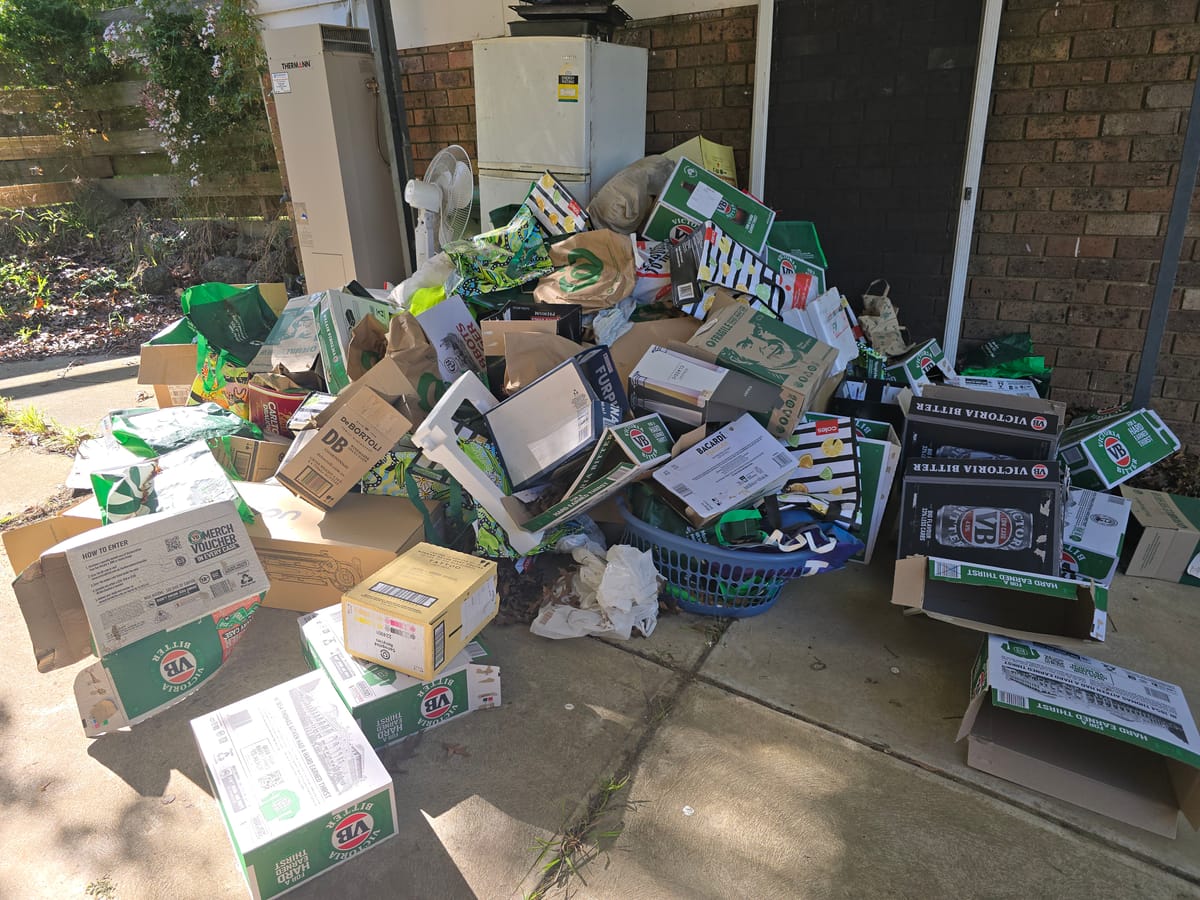 Cardboard boxes and household waste piled by a brick wall before rubbish removal in Melbourne