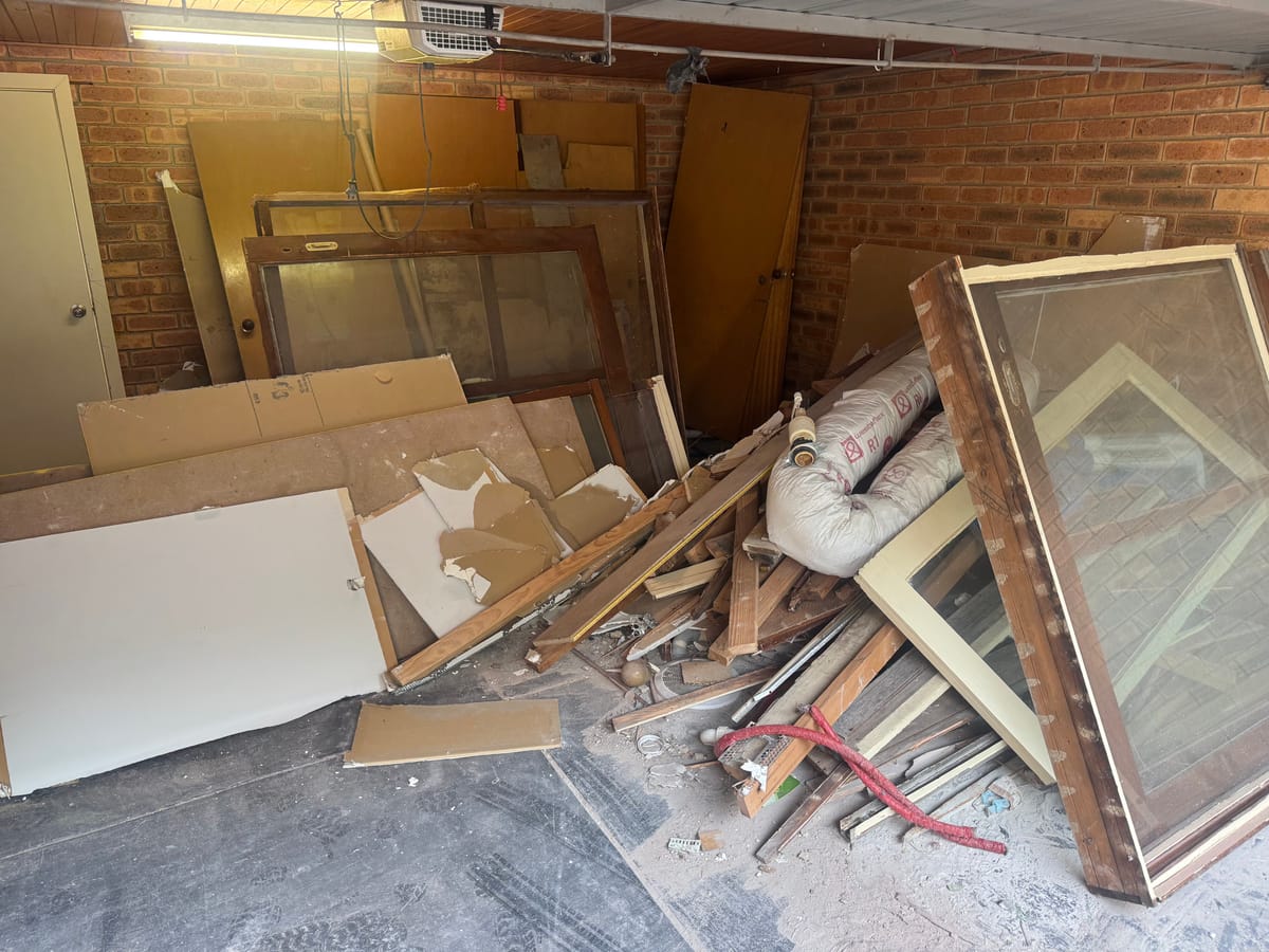 Room filled with old doors, window frames and renovation timber before waste removal in Melbourne